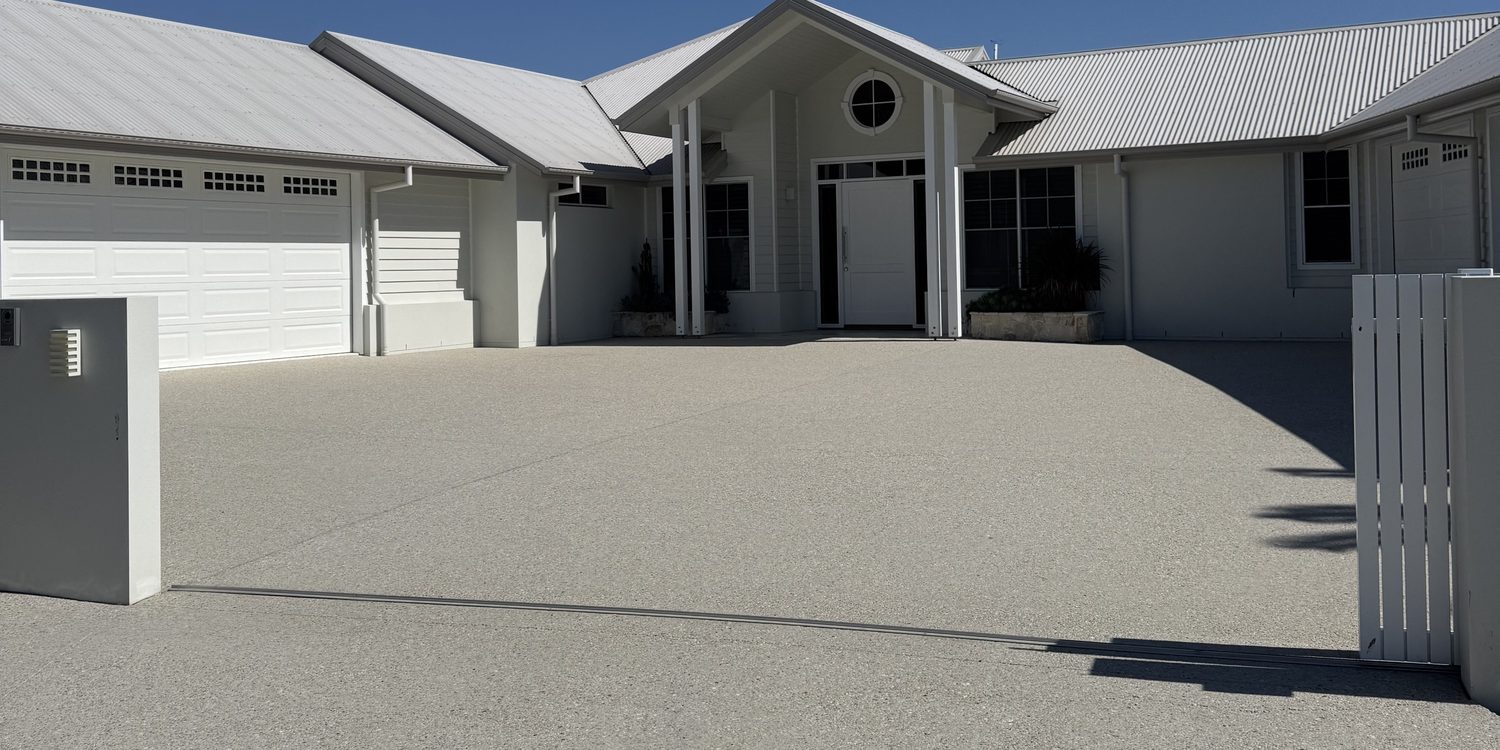 Clear sealed exposed-aggregate driveway at a white coastal-style home in Cleveland, QLD