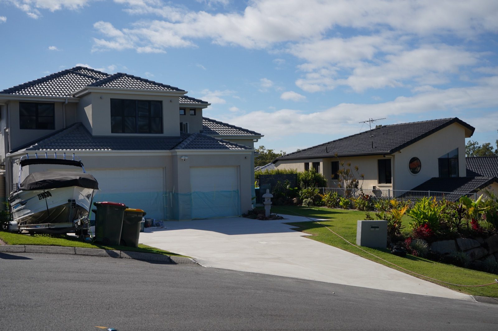 Freshly resurfaced pale grey concrete driveway at a two-storey Brisbane home in McDowall, garage doors masked during the job